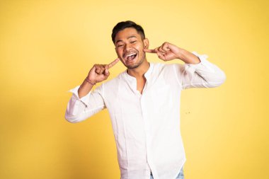 Asyalı genç adam parmak hareketleriyle gülüyor.