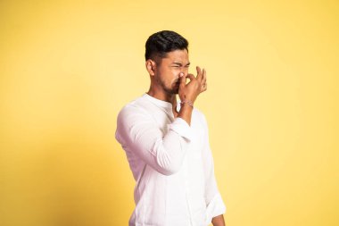 Hayal kırıklığına uğramış Asyalı genç adam, eli burnu kapalı.