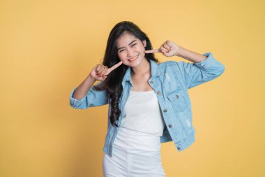 Yanağını gösteren iki parmağıyla gülümseyen tatlı bir genç kadın.