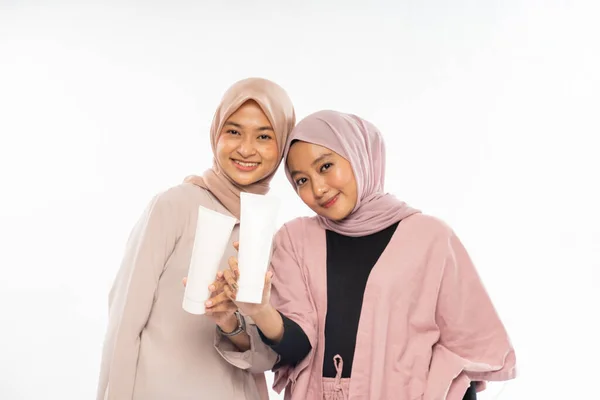 スキンケアのためのチューブ化粧品を持っている2人のイスラム教徒の美容友人 — ストック写真