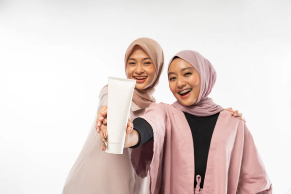 两个穆斯林美女朋友拿着用于护肤的管状化妆品 — 图库照片