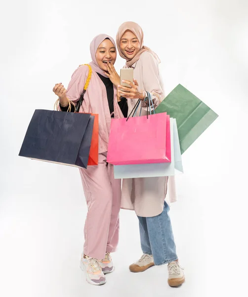 Junge muslimische Freundin benutzt Smartphone und hält Einkaufstasche — Stockfoto