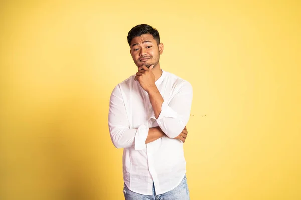 Asijský mladý muž s sarkastickým výrazem s rukou drží bradu — Stock fotografie