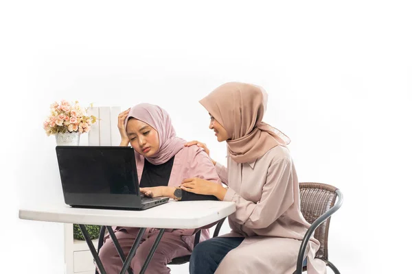 Muslimin tröstet ihren traurigen Freund, während sie an ihrem Laptop arbeitet — Stockfoto