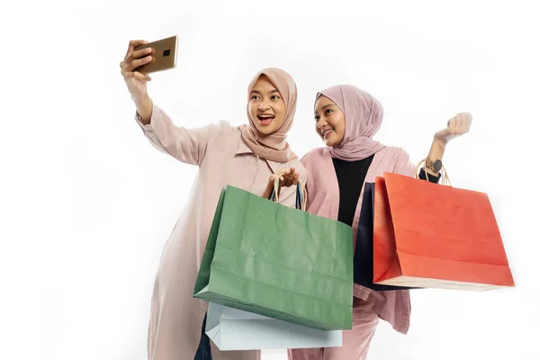 Asiático hijab mujer amigo tomar autorretrato usando móvil teléfono con bolsa de compras —  Fotos de Stock