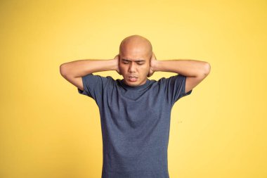 Elleri kulaklarını tıkayan kel bir adam.