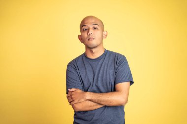 Tişörtlü kızgın kel adam kollarını kavuşturdu.