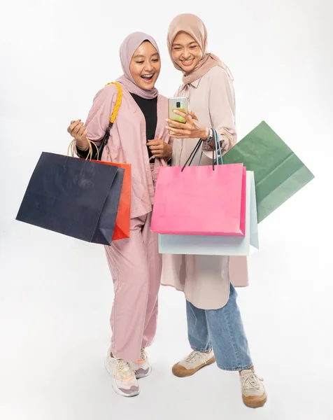 Musulmano giovane amico utilizzando smart phone e tenendo shopping bag — Foto Stock