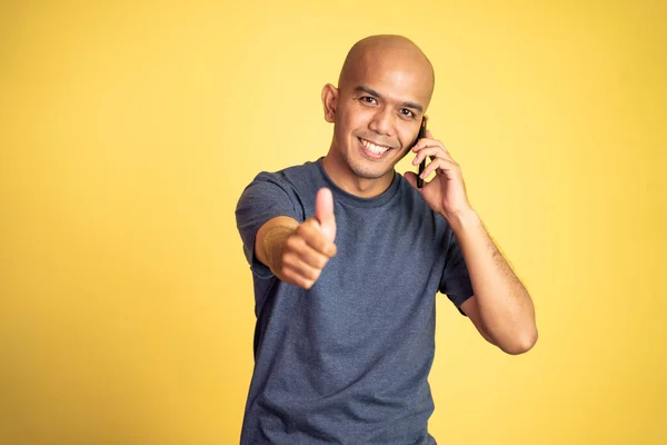 Feliz hombre calvo mostrando pulgares hacia arriba escuchando el teléfono móvil — Foto de Stock