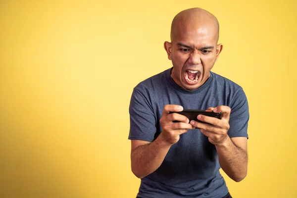 Akıllı telefon kullanarak oyun oynarken bağıran kel Asyalı adam. — Stok fotoğraf