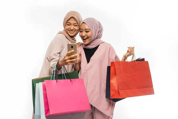 Jovem amigo muçulmano usando telefone inteligente e segurando saco de compras — Fotografia de Stock