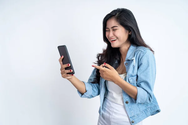 Jonge vrouw glimlachen met de vinger wijzen met behulp van een mobiele telefoon — Stockfoto