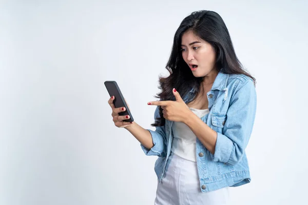 Jovem chocada com o dedo apontando usando um telefone celular — Fotografia de Stock