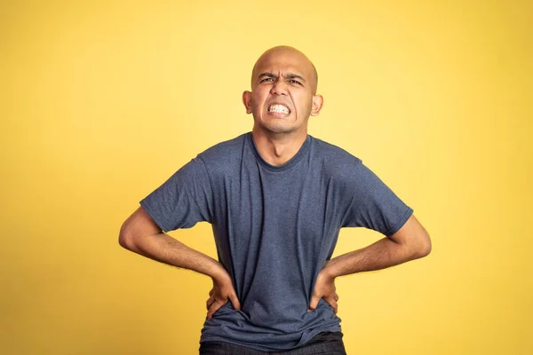 asian bald man having stomachache holding his stomach