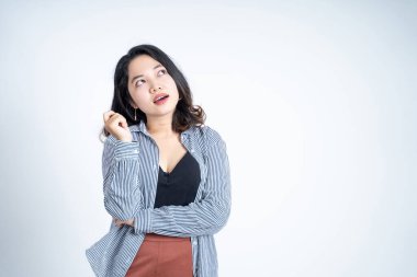 Genç Asyalı kadın tecrit edilmiş arka planda bir şey düşünüyor.