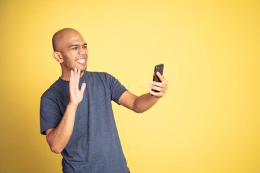 Heyecanlı Asyalı adam video çağrısında el sallıyor.