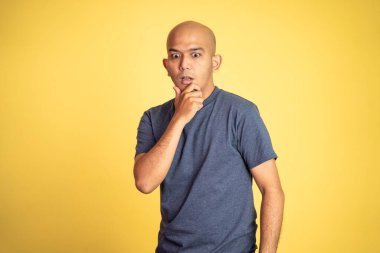 Şok olmuş Asyalı kel adam, elleri ağızda.