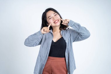 Gülümseyen genç kadın iki parmağıyla yanağını gösteriyor.