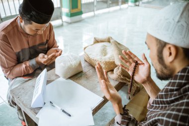 Camide sadaka veren Asyalı adam ve Tanrı 'ya dua eden.