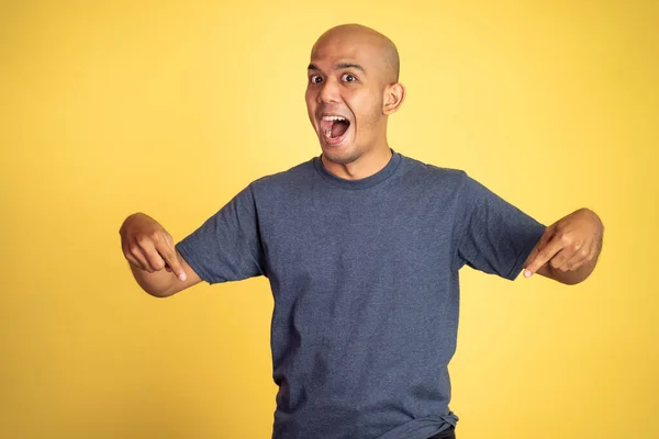 Excited bald young man with two fingers pointing down — Stock Photo, Image