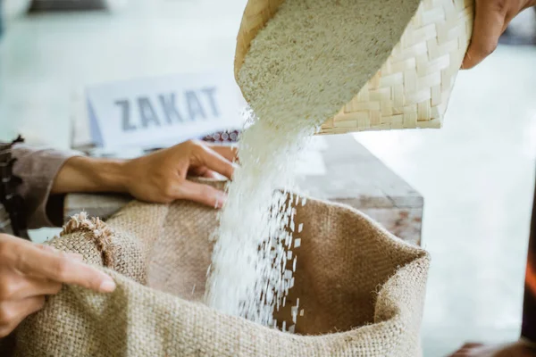 Eller, yoksullara yardım etmek için pirinç taneleri veriyor.