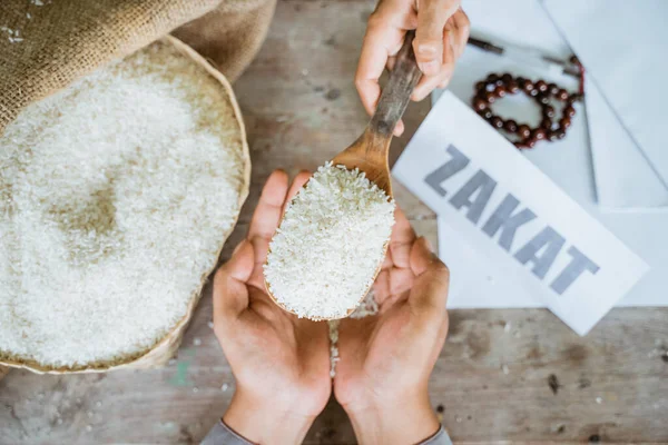 Mãos dando grãos de arroz para zakat ajudando os pobres — Fotografia de Stock