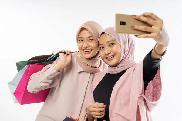 Asiático hijab mulher amigo tomar auto retrato usando celular com saco de compras — Fotografia de Stock