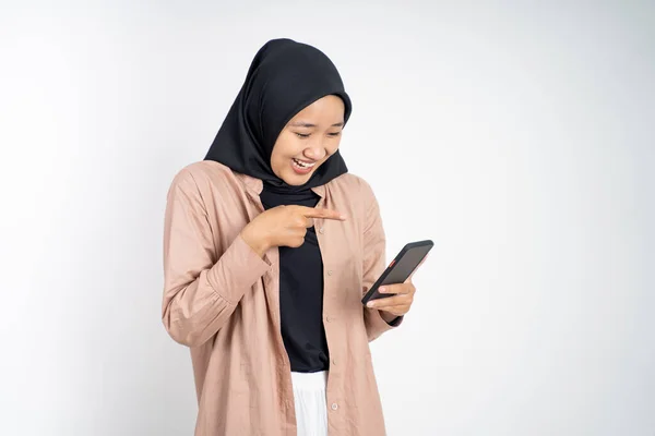 Moslim vrouw lachen om haar smartphone geïsoleerd op geel — Stockfoto