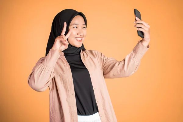 Woman in hijab holding a smart phone for selfie — Stock Photo, Image