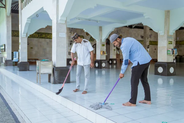 Muslim laki-laki membersihkan masjid menggunakan sapu dan menyapu lantai — Stok Foto