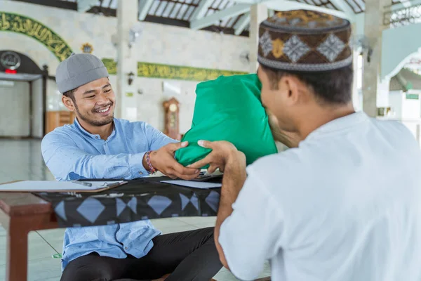 Muslim man som ger ett ris som en livsmedelsdonation för zakat under eid mubarak — Stockfoto