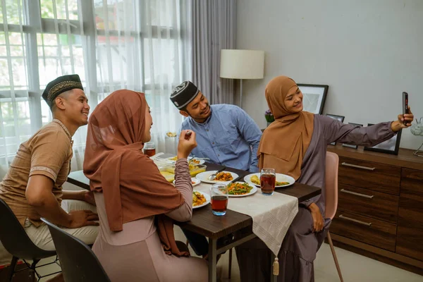 Teman makan malam iftar bersama-sama sambil duduk di lantai di ruang tamu — Stok Foto