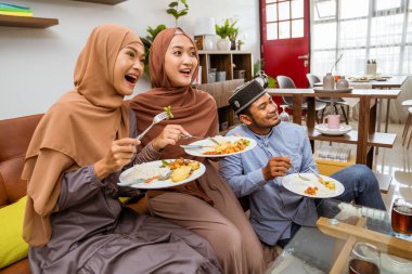 Müslüman insanlar kanepede iftar yemeği yiyor.