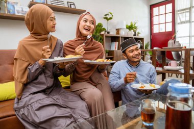 Müslüman insanlar kanepede iftar yemeği yiyor.
