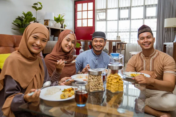 Teman makan malam iftar bersama-sama sambil duduk di lantai di ruang tamu — Stok Foto