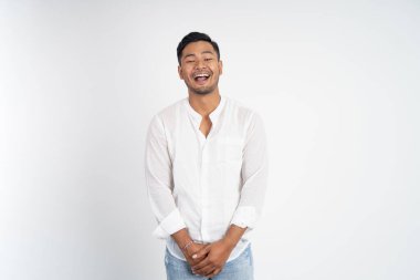 Mutlu Asyalı genç adam stüdyo arka planında doğal olarak gülüyor.