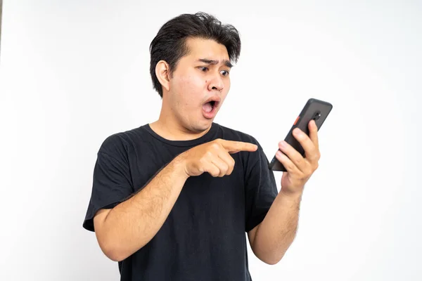 Joven asiático hombre shocked mientras mirando en smartphone pantalla —  Fotos de Stock