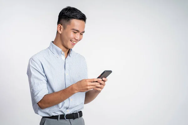 Šťastný asijský mladý muž při pohledu na obrazovku mobilního telefonu — Stock fotografie