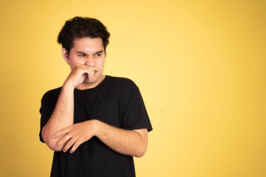 Asyalı kızgın genç adam elleriyle burnunu kapatıyor.