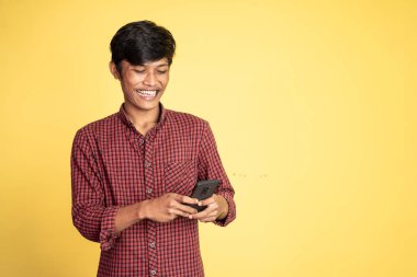 Mutlu Asyalı genç adam cep telefonunun ekranına bakıyor.