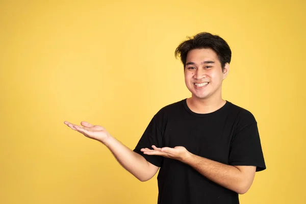 Azji człowiek uśmiecha się z obu rąk prezentując coś — Zdjęcie stockowe