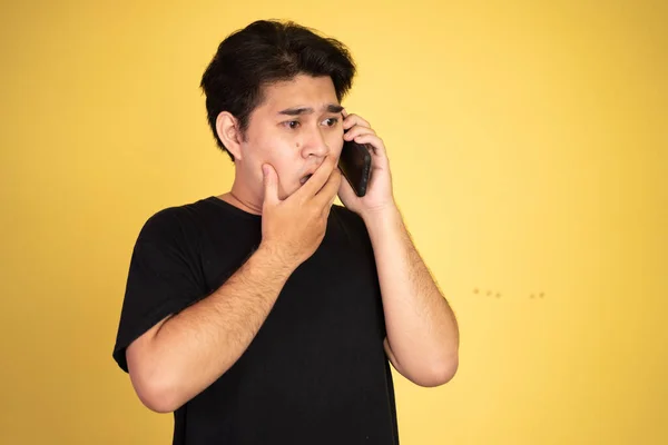 Asijský muž šokován při mluvení na svém smartphonu — Stock fotografie