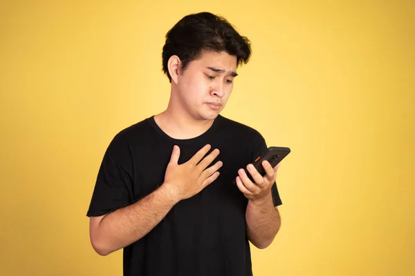 Jeune asiatique homme choqué tout en regardant smartphone écran — Photo
