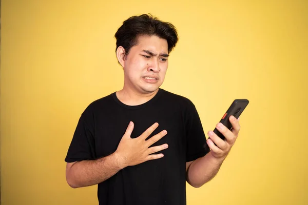 Young asian man shocked while looking at smartphone screen — Stock Photo, Image