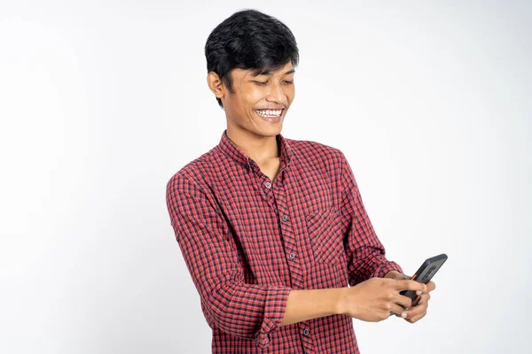 Glücklicher asiatischer junger Mann schaut auf den Bildschirm eines Mobiltelefons — Stockfoto