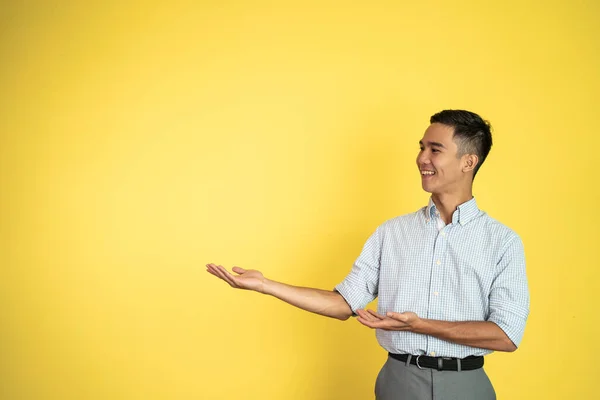 Asiatico uomo sorridente con entrambi mani presentazione qualcosa — Foto Stock