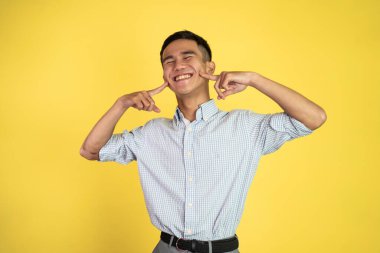 Gülümseyen ve tatlı bir jest yapan adam parmağını yanaklarına koydu.