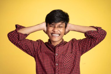 Stresli Asyalı genç adam başını tutuyor.