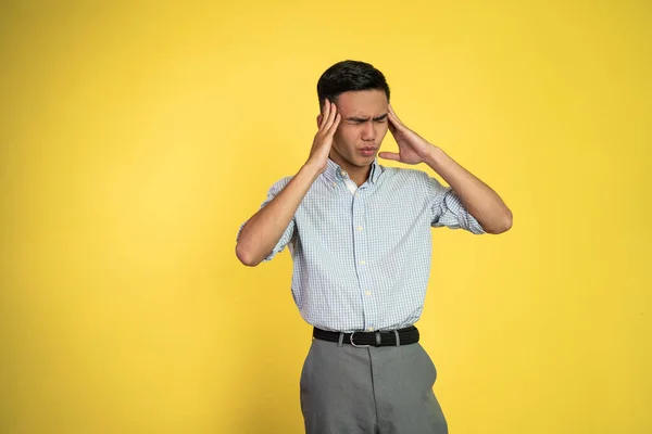 Stressad asiatisk ung man håller huvudet — Stockfoto