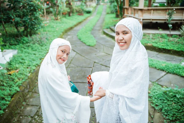 Madre e hija con hiyab caminando a la mezquita para hacer la oración idul fitri — Foto de Stock